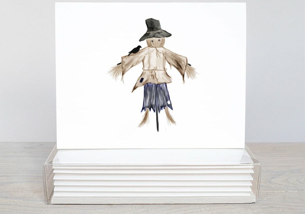 brown and blue scarecrow with a black crow on his shoulder on note card