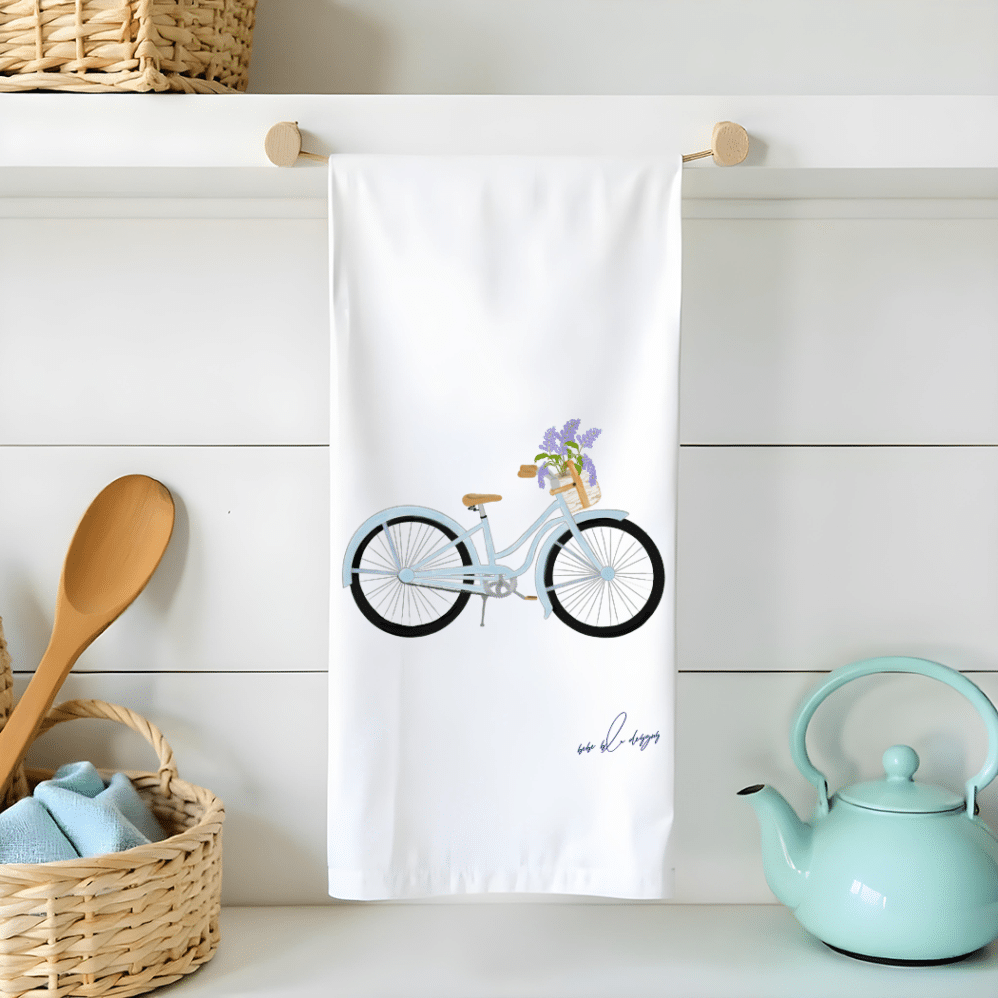 blue bicycle with basket of lilacs on a flour sack tea towel